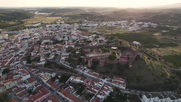 Sunset view of Silves Castle and sprawling Silves city, Algarve. Orbiting shot alt
