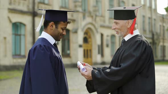 Eminent Professor Giving Diploma to Male Student Shaking Hand Convocation Day alt