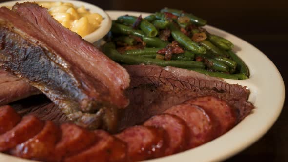 Texas barbecue plate, ribs sausage brisket with green beans and macaroni and cheese, close up slider alt