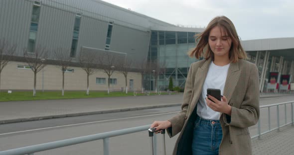 The Girl with the Suitcase Is Typing a Message and Going To Find Some Transport. Travel By Plane alt