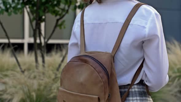 Teenage Girl with a Backpack on Her Shoulders Goes to School After Summer Vacation