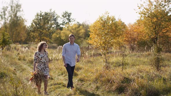 Positive Young Happy Loving Couple Walking on Meadow in Summer alt