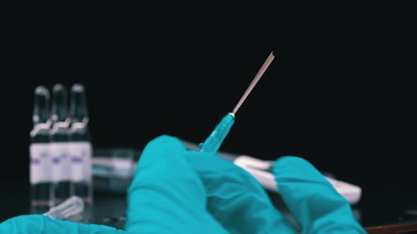 Nurse Prepares a Syringe And Medicine Drips From It in Large Drops Closeup alt