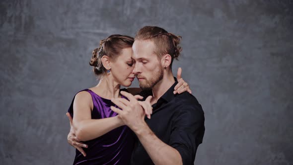 Tango Dancer Hugging a Woman on Her Back and Spinning in a Grey Studio