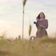 Beautiful Young Woman Walks in a Wheat Field