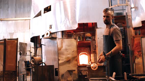 Glassblower shaping a molten glass alt