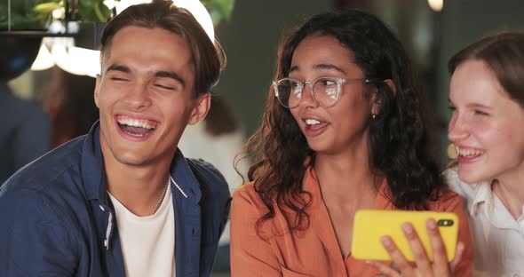 Close Up View of Cheerful Young People Communicating and Laughing While Looking at Phone Screen alt