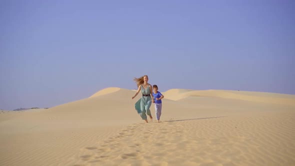Slowmotion Shot of a Young Woman and Little Boy Having Fun in a Desert alt