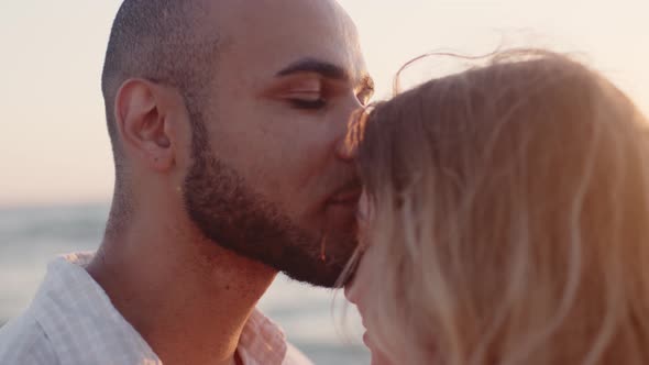 Young Black Man Kissing His Caucasian Girlfriend on Beach By the Sea