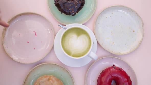 Assorted Vegan Doughnuts Served Around Cup of Matcha Latte on Pastel Pink Table alt
