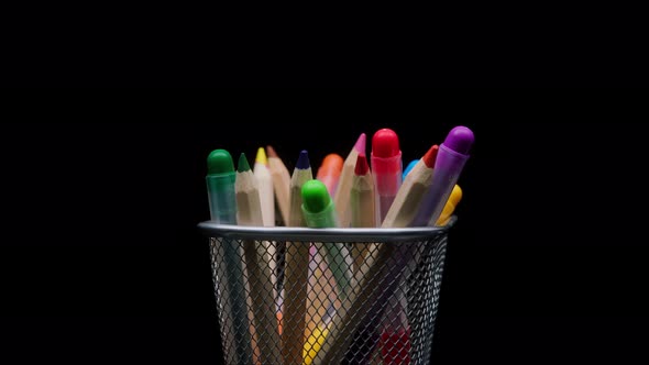 Closeup of Colored Pencils and Markers in a Metal Grey Basket Shooting Stationery on Black alt