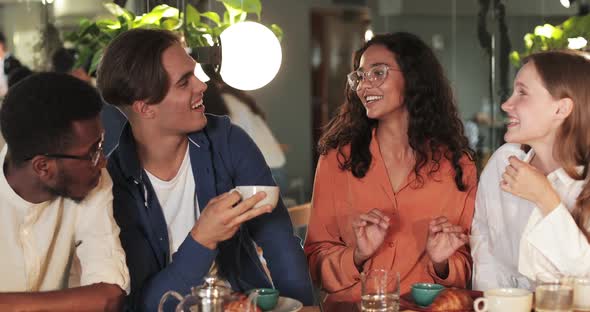 Crop View of Beautiful Woman in Glasses Gesturing While Telling Funny Story Her Friends in Cosy Cafe alt