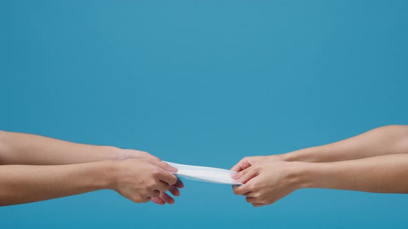 Young woman hand holding protection face mask isolated over blue background in studio. alt