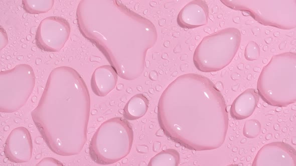 Macro Shot of Cosmetic Moisturizing Drops of Liquid on a Pink Pastel Background alt