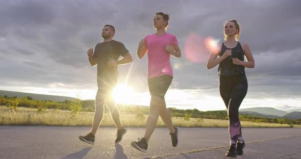 Multiethnic Group of Athletes Running Together on a Panoramic Countryside Road alt