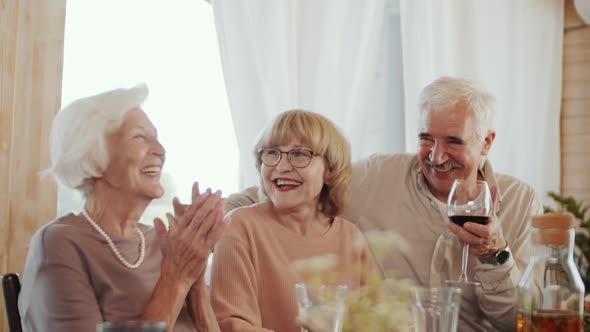 Senior Family Members Smiling and Chatting over Wine at Holiday Dinner alt