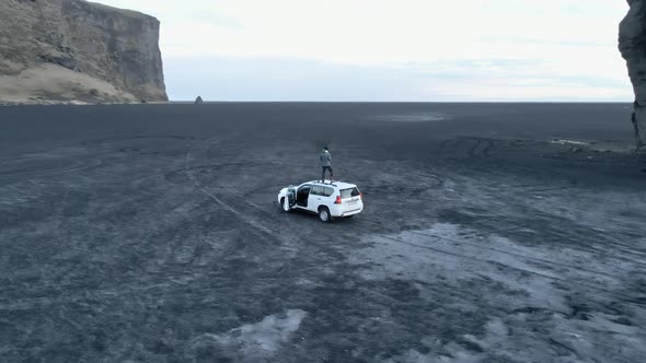 Man on Top of White Van with Sea Stack and Cliff in View alt