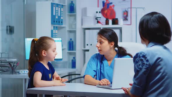 Nurse Talking with Child and Writing on Laptop alt