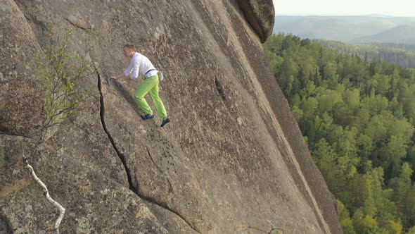 Aerial View of a Young Brave Man Climbing a Rock Wall Without Insurance. Extreme Ascent To the Top