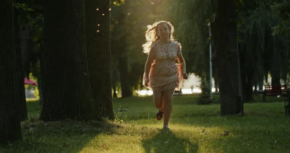 Cheerful Young Girl Running To Camera in Summer Park alt