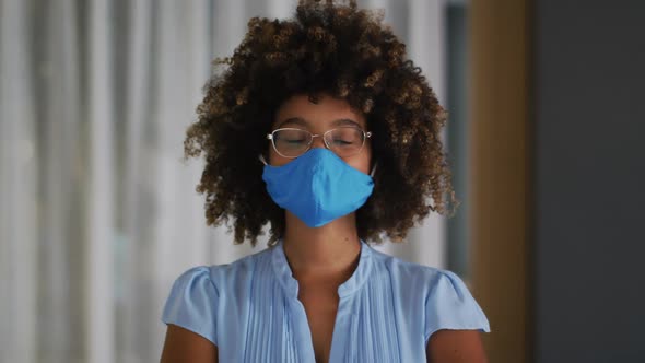 Portrait of mixed race woman with curly hair wearing blue face mask alt