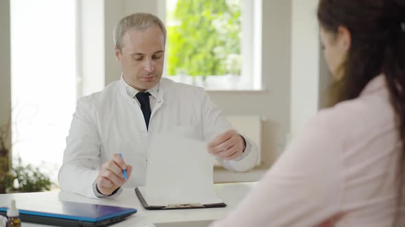 Portrait of Serious Mid-adult Doctor Looking Through Patient's Examination Results and Shaking Head alt