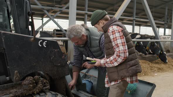 Boy Helping Father Fixing Tractor at Cattle Farm alt