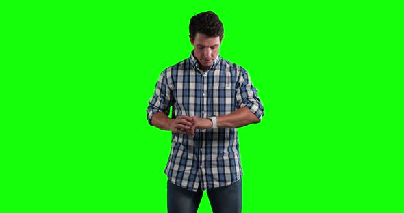 a Caucasian man checking his smartwatch in a green background
