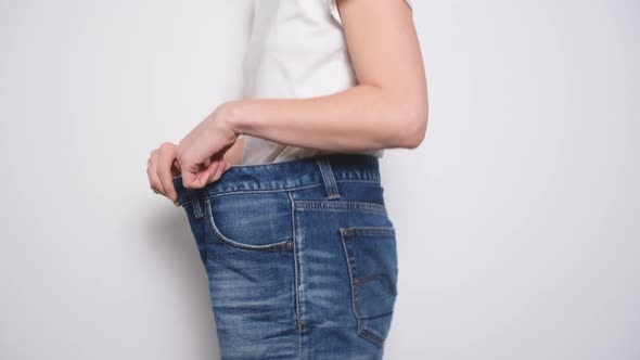 Happy Woman Dancing in Oversized Jeans on White Background