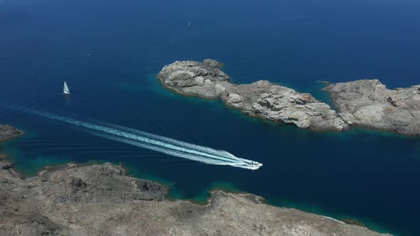 Aerial View of Boat Sailing Along Rocky Sea Coast alt