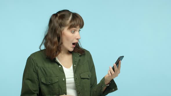 Slow Motion of Funny Young Woman Reading Smartphone and Looking Surprised Pointing Finger at Mobile
