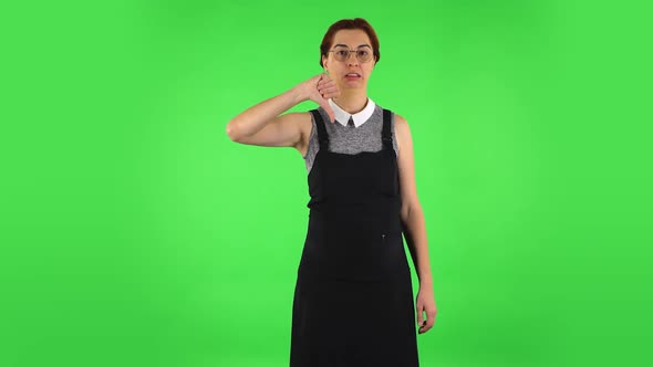 Funny Girl in Round Glasses Is Showing Thumbs Down Gesture. Green Screen alt
