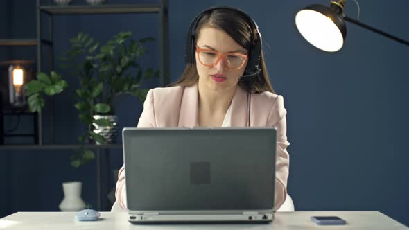 Portrait of a Young Woman in a Headset Working at a Laptop