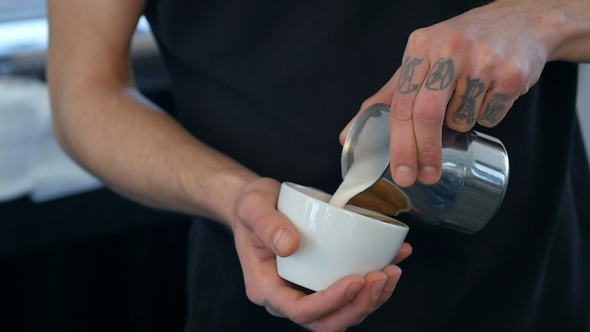Barista making coffee, pouring milk into a cup