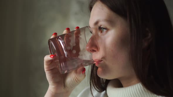 Woman with Pleasure, at Home in the Room Drinks Water From a Glass Goblet