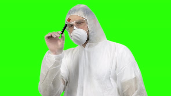 Researcher or Scientist in Protective Clothing Looking at Blood Test Tube alt