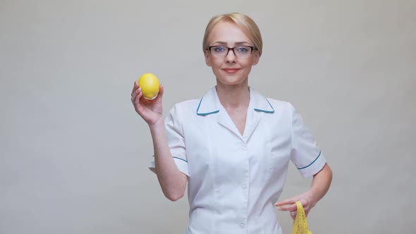 Nutritionist Doctor Healthy Lifestyle Concept - Holding Organic Lemon Fruit and Measurng Tape alt