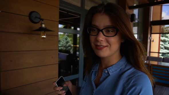 Gladden Female Customer Leaving Restaurant with Satisfied Face and Smartphone