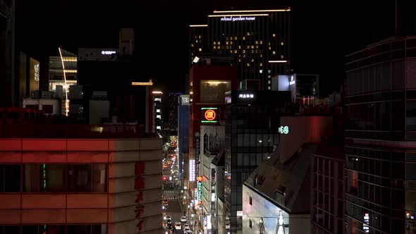 Tokyo Street at Night with Illuminated Neon Sign and High Rise Buildings alt