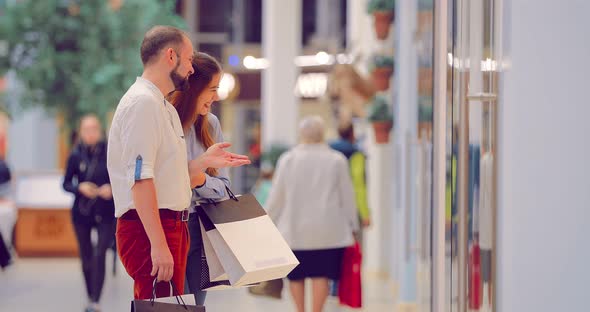 Attractive Couple in the Mall is Standing and Discussing Something Near the Wind Screen alt