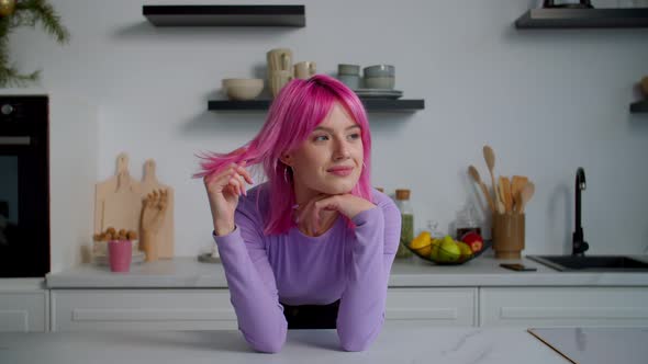 Portrait of Dreamy Lovely Pink Haired Young Woman Smiling in Kitchen alt