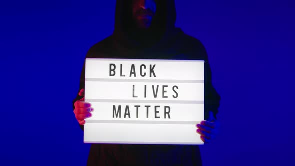 Dramatic Man in Hood Hold Black Lives Matter Sign alt