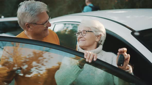 Senior Couple Purchased New Car. Standing Near the Door and Woman Holding Keys alt