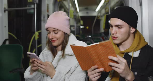 Millennial Guy Using Reading Book While Sitting Near His Lovely Girlfriend. Young Pretty Girlusing alt