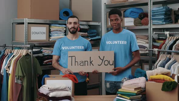 Portrait View of the Diverse Male Volunteers Holding Cupboard Banner with Thank you Phrase and alt