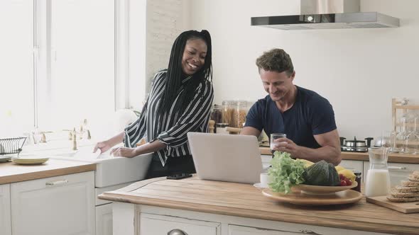Interracial couple talking and looking at cell phone together while doing daily morning routine