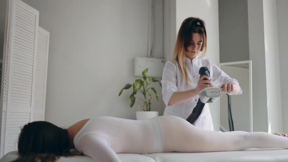 Adult Woman is Relaxing During Anticellulite Massage in Beauty Clinic Body Care and Apparatus Lost alt