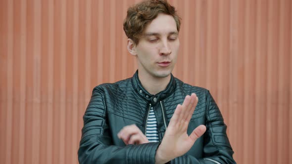 Portrait of Serious Guy Saying No and Crossing Arms Speaking and Looking at Camera Outdoors alt
