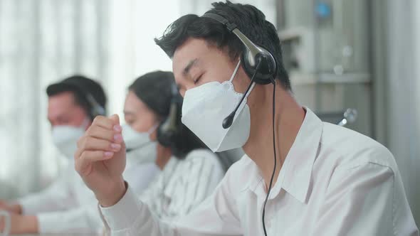 Man Of Three Asian Call Centre Agents In Mask Headache Because His Colleagues Are Talking alt