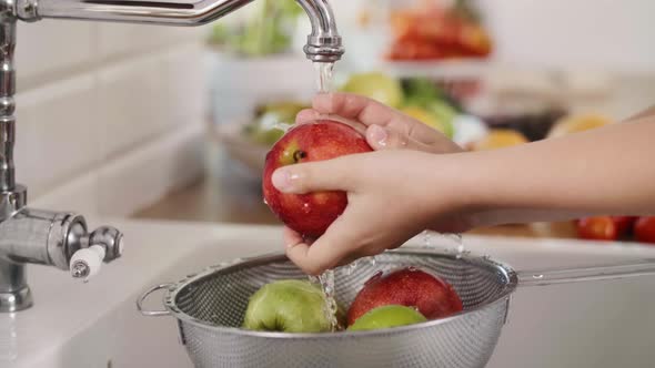 Handheld view of woman washing seasonal fresh apples alt